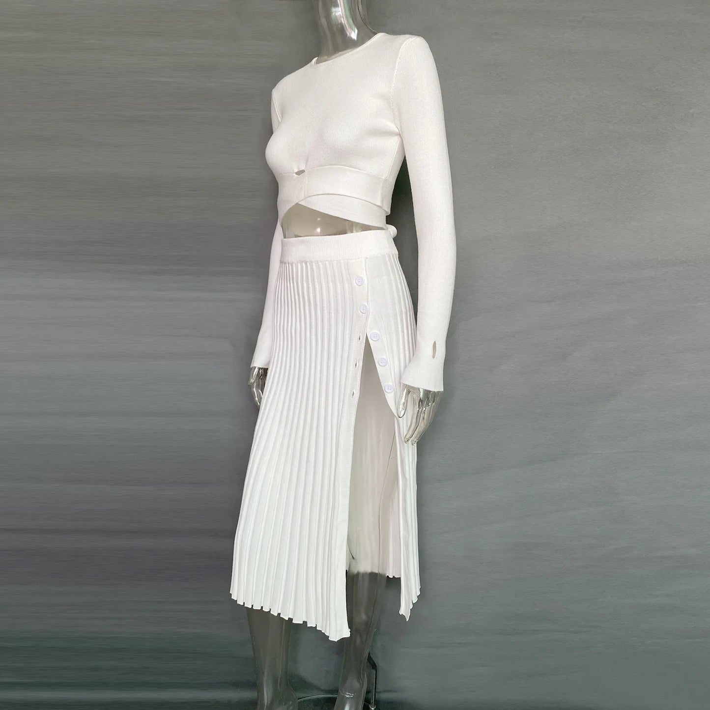 Get ready to fall in love with the 'Tossy'—a chic, white knit two-piece set for women. This ensemble features a ribbed crop top paired with a pleated midi skirt, perfect for those crisp autumn days. It's the ultimate blend