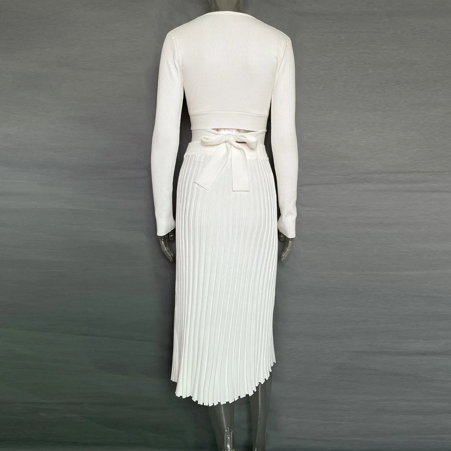 Get ready to fall in love with the 'Tossy'—a chic, white knit two-piece set for women. This ensemble features a ribbed crop top paired with a pleated midi skirt, perfect for those crisp autumn days. It's the ultimate blend